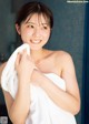 A woman wrapped in a white towel in a bathroom.