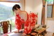 A woman in a red kimono sitting at a table.