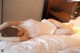 A woman laying on a bed in a white lingerie.