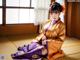 A woman in a kimono sitting on a tatami mat.