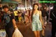 A woman walking down a crowded street at night.