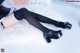 A woman wearing black stockings and high heels laying on a white rug.