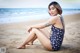 A woman sitting on the beach in a bathing suit.