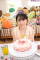 A woman sitting at a table with a birthday cake.