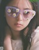 A young woman wearing a pair of sunglasses with daisies on them.