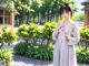 A woman in a white kimono standing in a garden.