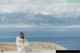 A woman sitting on top of a wooden platform next to the ocean.