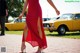 A woman in a red dress is walking down the street.